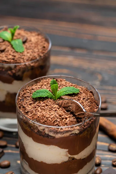 Klassisches Tiramisu-Dessert in einer Glasschale und Schokoladenstückchen auf Holzgrund — Stockfoto