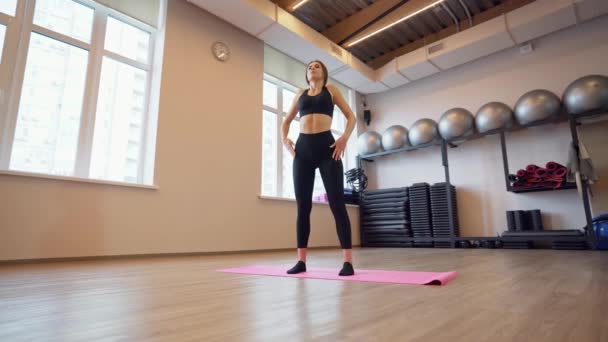 Beautiful young woman working out and stretching indoors — Stock Video