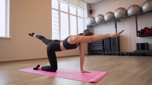 4x cámara lenta de vídeo de Hermosa mujer joven haciendo ejercicio y estiramiento en el interior — Vídeos de Stock