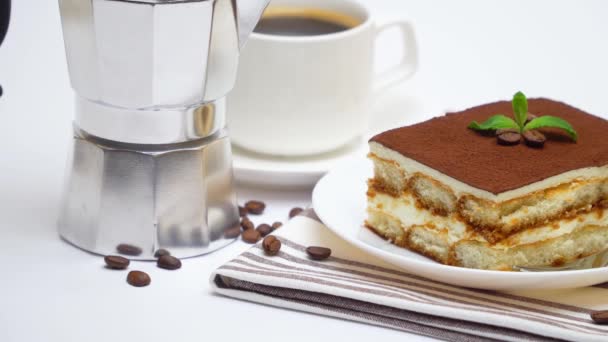 Μερίδιο γλυκού τιραμισού, καφετιέρα μόκα και φλιτζάνι καφέ φρέσκου espresso σε λευκό φόντο — Αρχείο Βίντεο