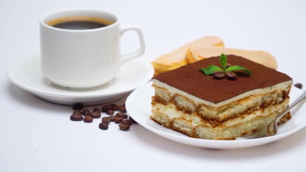 Tiramisu tatlı kare porsiyonu, savoiardi kurabiyeleri ve beyaz arka planda izole edilmiş bir fincan kahve. — Stok video