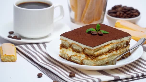 Tiramisú postre porción cuadrada, galletas savoiardi y taza de café sobre fondo blanco — Vídeo de stock