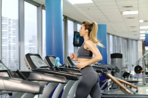 Ung sportig kvinna på löpning maskin i gym — Stockfoto