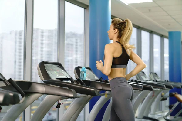 Ung sportig kvinna på löpning maskin i gym — Stockfoto