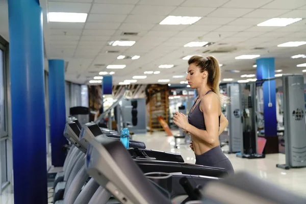 Ung sportig kvinna på löpning maskin i gym — Stockfoto