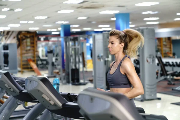 Jovem desportivo mulher no correndo máquina no ginásio — Fotografia de Stock