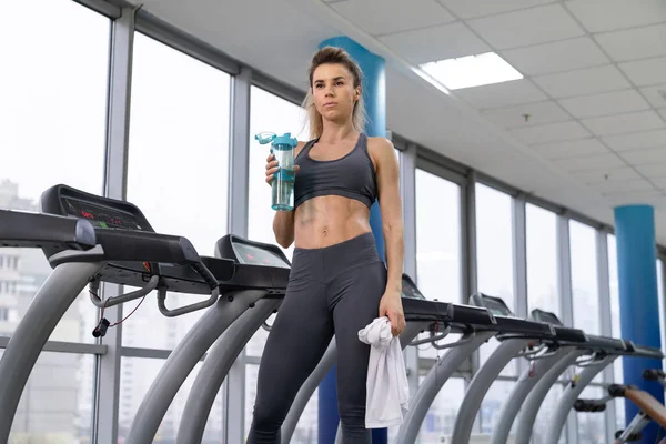 Turnerin trainiert Trinkwasser im Stehen an Fitnessgeräten — Stockfoto