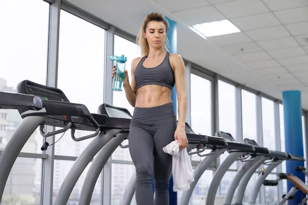 Turnerin trainiert Trinkwasser im Stehen an Fitnessgeräten — Stockfoto