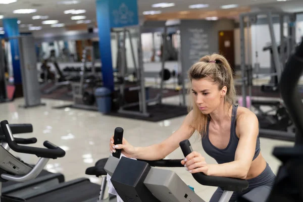 Ung kvinna på cykel på gym träning — Stockfoto