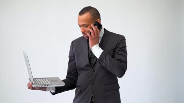 Профессиональный афро-американский бизнесмен держит ноутбук и разговаривает по телефону — стоковое видео