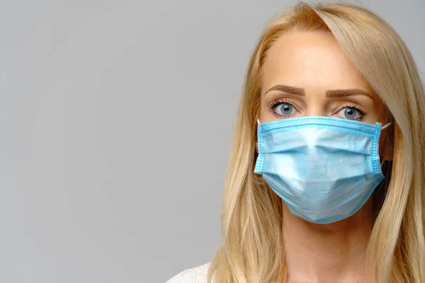 Retrato de estúdio de uma jovem mulher usando uma máscara protetora facial isolada em fundo cinza proteção contra epidemias de vírus da gripe, poeira ou alergia ao pólen, poluição do ar — Fotografia de Stock