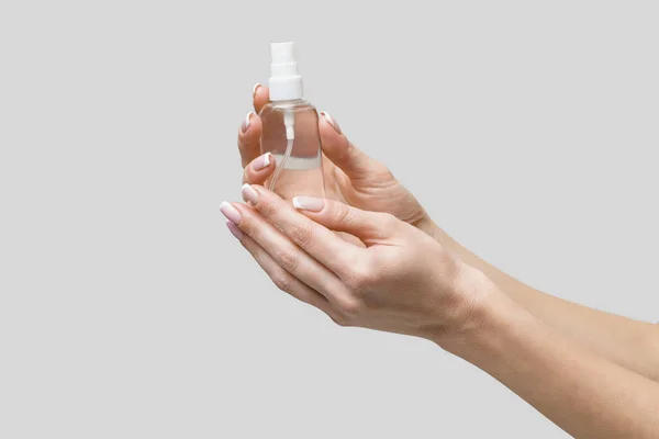 Mani femminili utilizzando erogatore spray disinfettante mano su sfondo grigio chiaro — Foto Stock