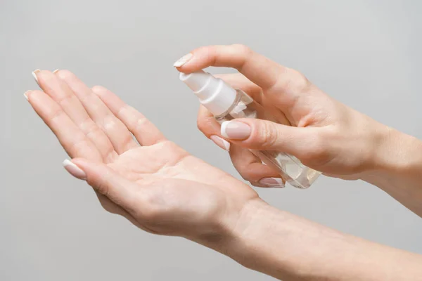 Weibliche Hände mit Händedesinfektionsspray-Spender über hellgrauem Hintergrund — Stockfoto