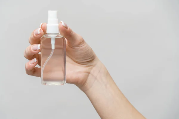 Mani femminili utilizzando erogatore spray disinfettante mano su sfondo grigio chiaro — Foto Stock