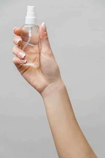 Female hands using hand sanitizer spray dispenser over light grey background — Stock Photo, Image