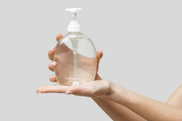 Mains féminines utilisant un gel désinfectant pour les mains ou un distributeur de savon liquide sur fond gris clair — Photo