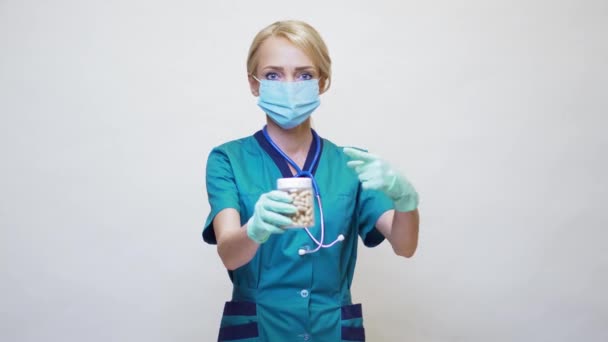 मेडिकल डॉक्टर नर्स महिला सुरक्षात्मक मास्क और रबर या लेटेक्स दस्ताने पहने हुए - होल्डिंग गोलियां — स्टॉक वीडियो