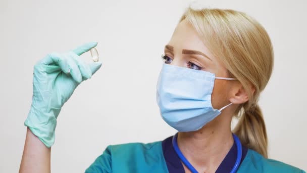 Лікар медсестра жінка в захисній масці і гумі або латексних рукавичках тримає таблетки — стокове відео