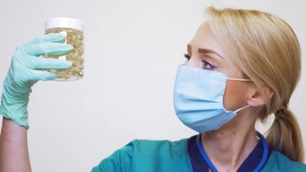 Medical doctor nurse woman wearing protective mask and rubber or latex gloves - holding pills — Stock Video
