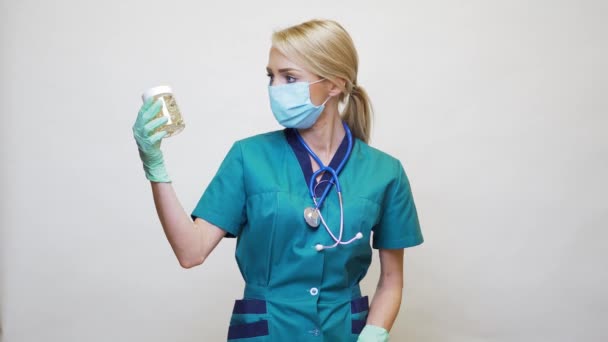 Médecin infirmière femme portant un masque protecteur et des gants en caoutchouc ou en latex - tenant des pilules — Video