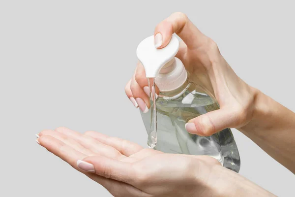 Mains féminines utilisant un gel désinfectant pour les mains ou un distributeur de savon liquide sur fond gris clair — Photo