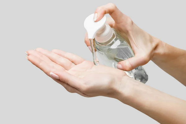 Mains féminines utilisant un gel désinfectant pour les mains ou un distributeur de savon liquide sur fond gris clair — Photo