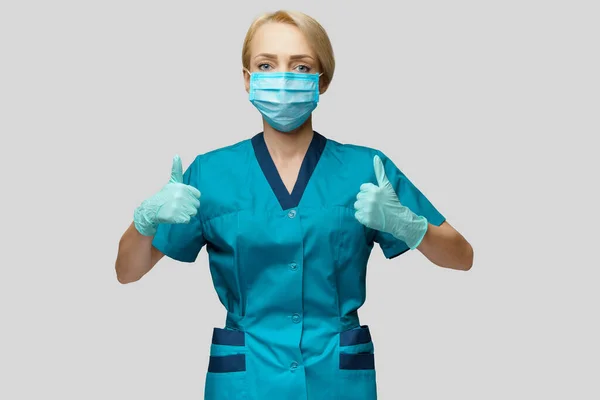 Médecin infirmière femme portant un masque de protection et des gants en latex - montrant grand pouce vers le haut — Photo