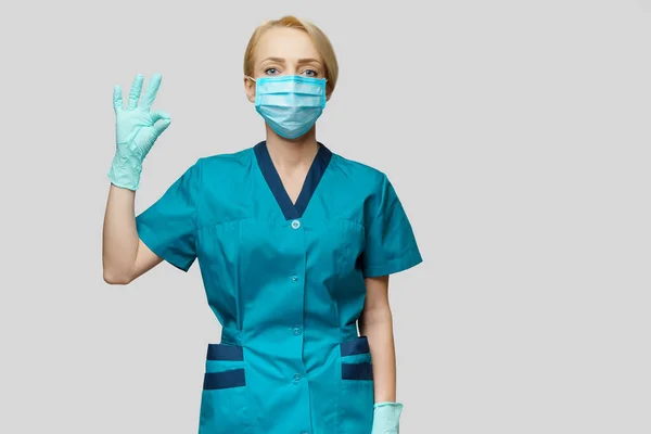 Médecin infirmière femme portant un masque de protection et des gants en latex - montrant OK signe — Photo