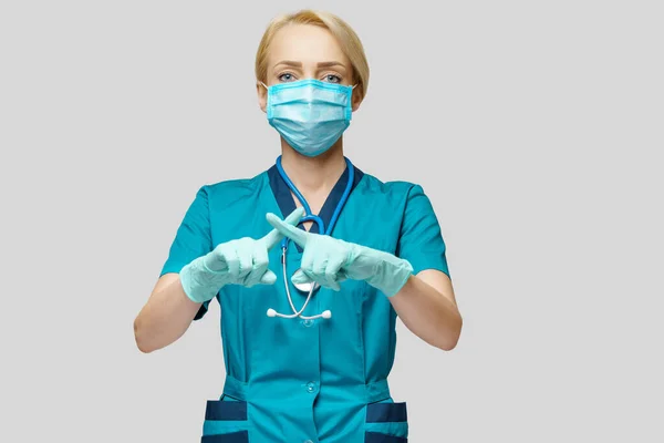 Arts verpleegkundige vrouw met beschermend masker en rubber of latex handschoenen - stopteken gebaar — Stockfoto