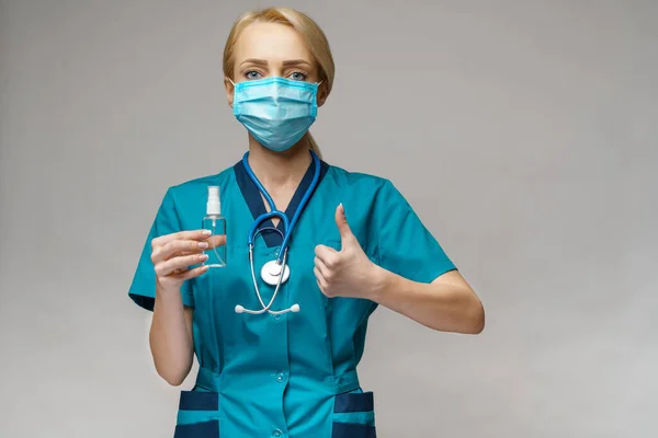 Medical doctor nurse wearing protective mask - holding bottle of sanitizing spray or gel — Stock Photo, Image