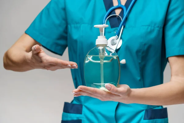 Lékařský lékař zdravotní sestra nosí ochrannou masku - držení sanitační sprej nebo gel nebo tekuté mýdlo — Stock fotografie