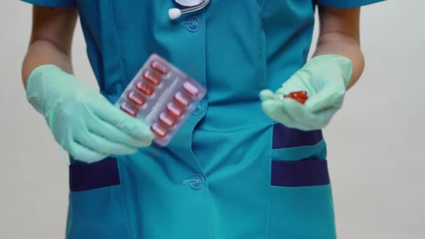 Medico infermiere donna indossando maschera protettiva e guanti di gomma o lattice - tenendo pillole — Video Stock