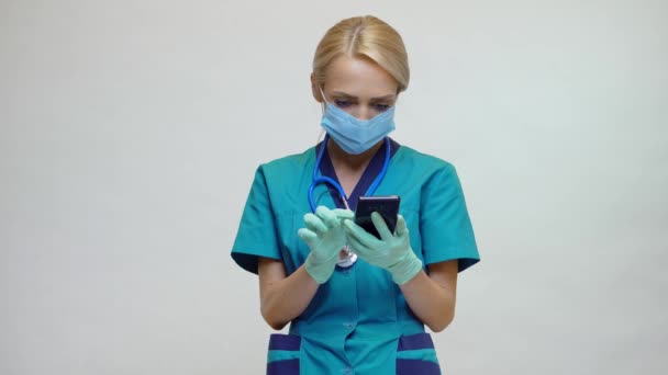 Medico infermiera donna indossando maschera protettiva e guanti di lattice - parlando al telefono — Video Stock