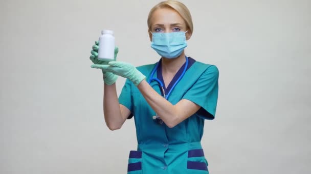 Läkare sjuksköterska kvinna bär skyddande mask - innehavande burk med piller eller vitaminer — Stockvideo