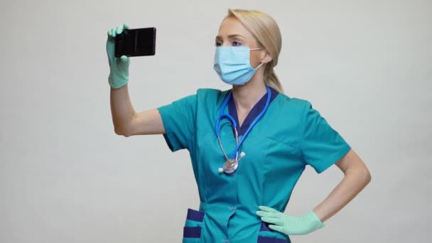 Medico infermiera donna indossando maschera protettiva e guanti in lattice - fare videochiamate al telefono — Video Stock