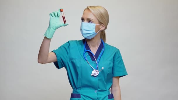 Médecin infirmière femme portant un masque protecteur et des gants en latex tenant tube à essai sanguin — Video