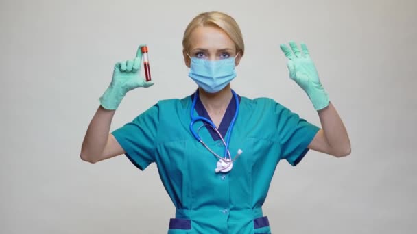 Médico enfermera mujer con máscara protectora y guantes de látex - sosteniendo el tubo de análisis de sangre — Vídeo de stock
