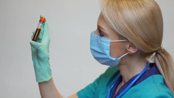 Médico enfermera mujer con máscara protectora y guantes de látex - sosteniendo el tubo de análisis de sangre — Vídeo de stock
