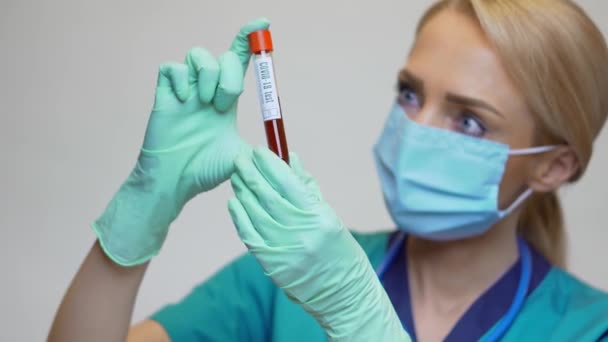 Perawat medis wanita perawat mengenakan topeng pelindung dan sarung tangan memegang COVID-19 tes darah — Stok Video