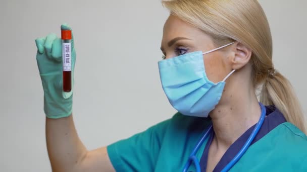 พยาบาลแพทย์หญิงพยาบาลสวมหน้ากากป้องกันและถุงมือ ถือการทดสอบเลือดโควิด-19 — วีดีโอสต็อก