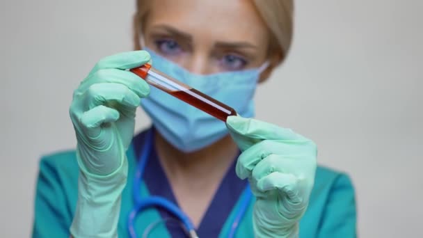Médico enfermeira mulher vestindo máscara protetora e luvas de látex - segurando tubo de teste de sangue — Vídeo de Stock
