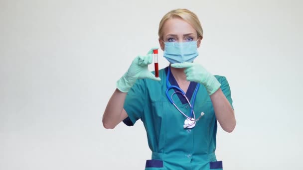 Medico infermiere donna indossando maschera protettiva e guanti di lattice - tenendo la provetta del sangue — Video Stock