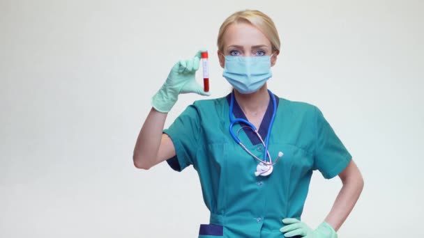 Médico enfermera mujer usando máscara protectora y guantes - sosteniendo COVID-19 positivo análisis de sangre — Vídeos de Stock
