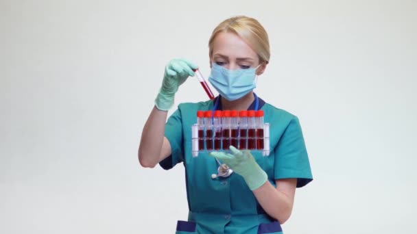 Médico enfermera mujer con máscara protectora y guantes de látex - celebración de estante de tubo de análisis de sangre — Vídeo de stock