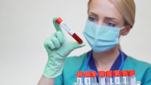 Medical doctor nurse woman wearing protective mask and latex gloves - holding blood test tube rack — Stock Video