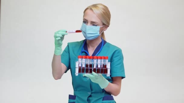 Läkare sjuksköterska kvinna bär skyddande mask och latexhandskar - håller blodprov röret rack — Stockvideo