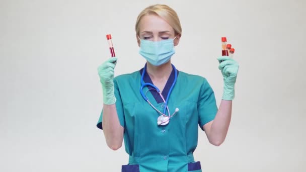 Koruyucu maske takan ve lateks eldiven takan Doktor Hemşire Kadın Kan Test Tüpü Tutuyor — Stok video