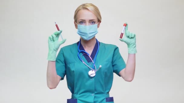 Médico enfermeira mulher usando máscara protetora e luvas de látex - segurando tubo de teste de sangue e seringa — Vídeo de Stock