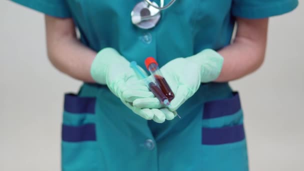 Medico infermiera donna indossando maschera protettiva e guanti di lattice - tenendo la provetta di sangue e siringa — Video Stock