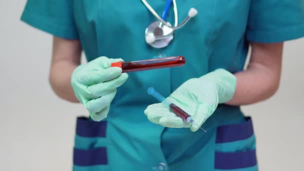 Doctor nurse woman wearing protective mask and latex gloves - holding blood test tube and syringe — Stock Video